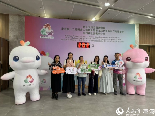 圖為參加培訓(xùn)的澳門賽區(qū)部分志愿者在倒計(jì)時(shí)牌前，與賽事吉祥物合影。人民網(wǎng)記者 富子梅攝