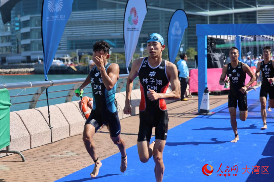 鐵人三項男子個人賽選手游泳上岸后奔向自行車項目轉(zhuǎn)換區(qū)。人民網(wǎng)記者 馮學(xué)知攝