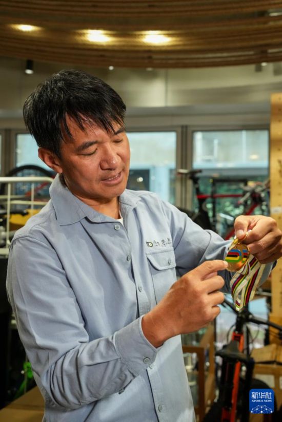 10月13日，在香港荃灣環(huán)貿(mào)廣場(chǎng)，黃金寶在他經(jīng)營(yíng)的單車店內(nèi)介紹獎(jiǎng)牌。新華社記者 朱煒 攝